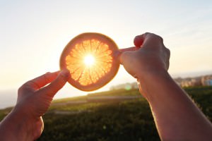 Due mani sollevano una fetta di arancia in controluce